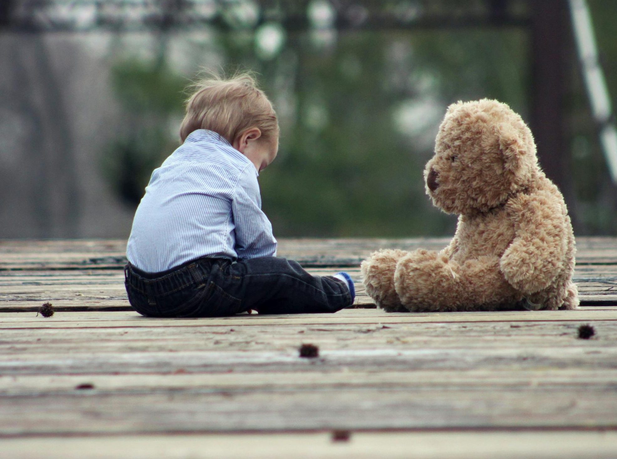 Boy Sitting With Brown Bear Plush Toy on Selective Focus Photo